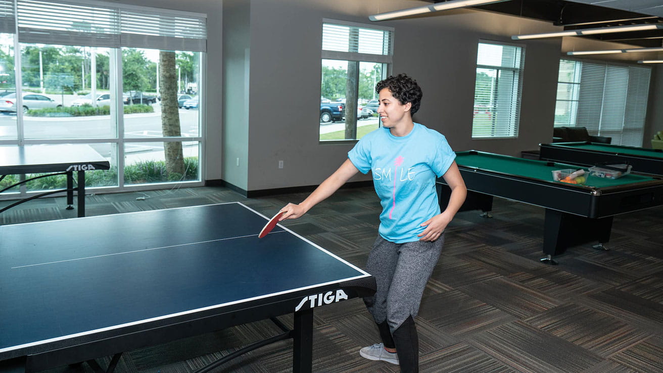 A student plays ping pong in the common area