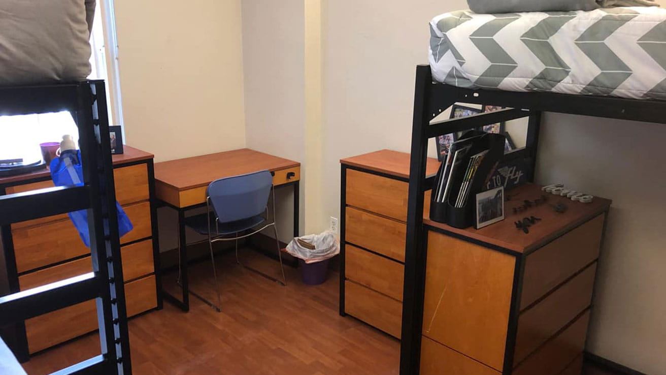A room with bunk beds, desks and dressers in Adams and Wood Hall