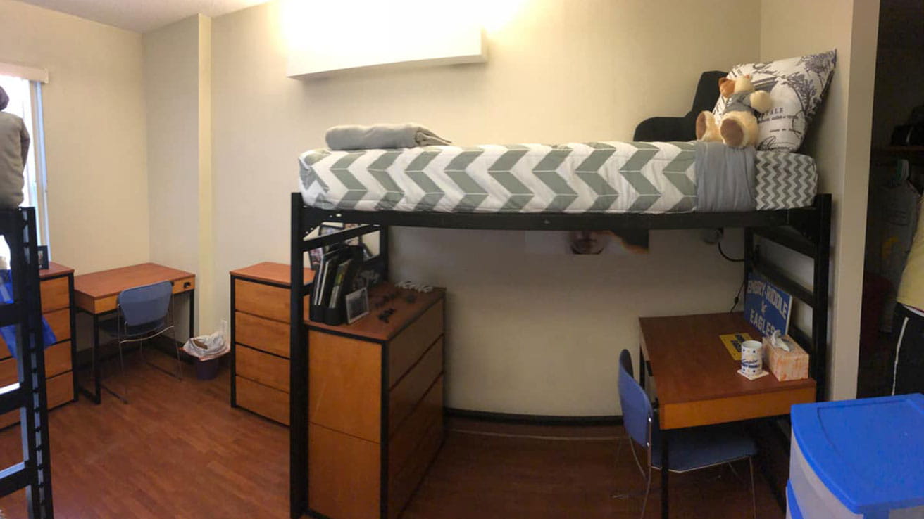 A room with a lofted bed, desk and dressers in Adams and Wood Hall