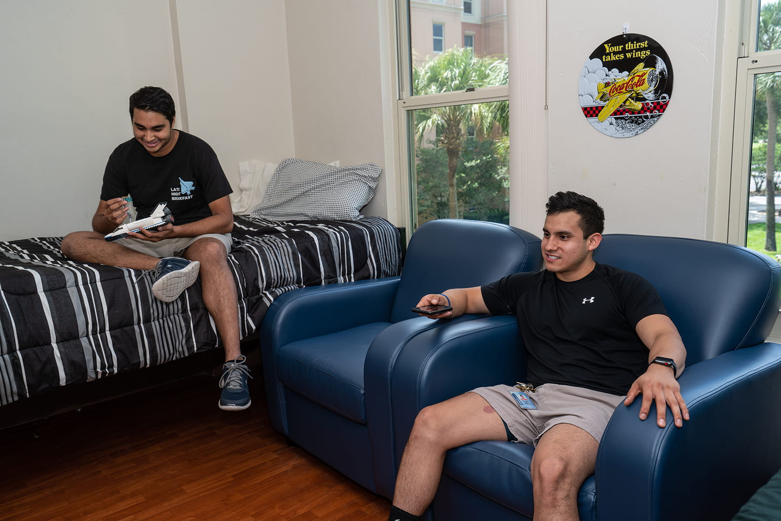 Two students hang out, watching TV and reading, in a room in Stimpson Hall