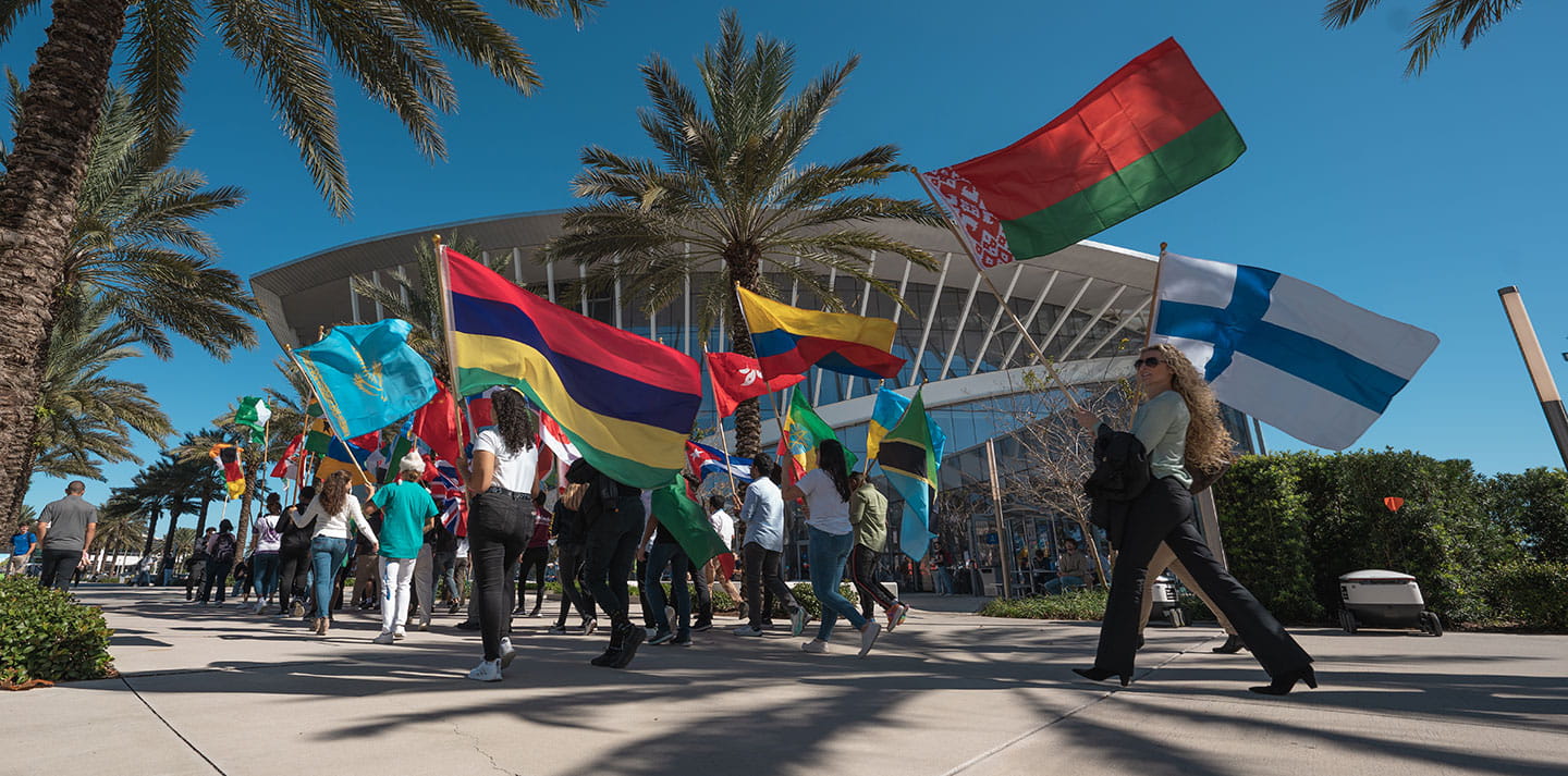 Students walk in front of the Student Union with flags from different countries