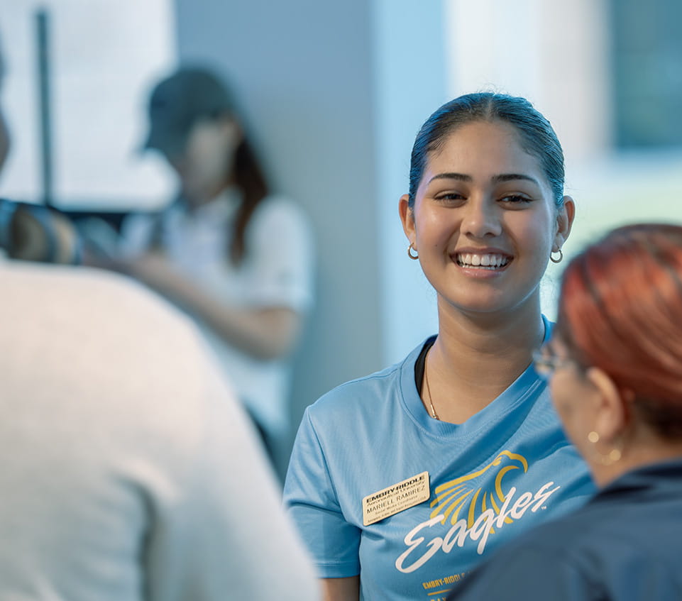 A person with an Embry-Riddle name badge smiles broadly, wearing an Eagles t-shirt.