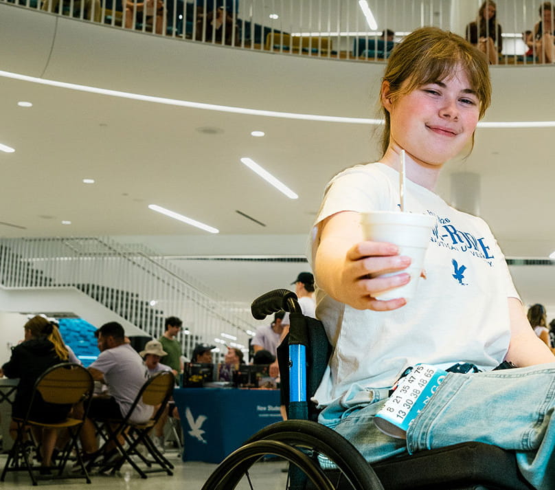 Embry-Riddle student in a wheelchair holds a drink towards the camera