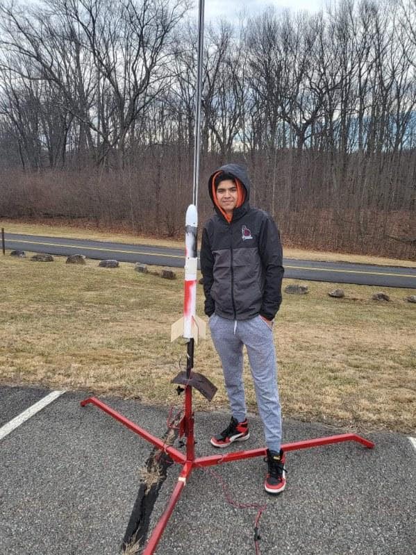 Adam Jain is shown standing next to a launch-ready model rocket near his high school in Morristown, New Jersey.