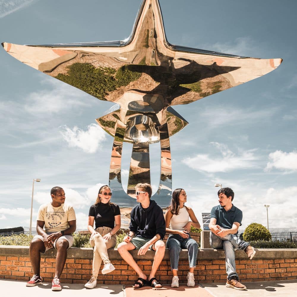 Students at Embry-Riddle's Daytona Beach Campus sitting together outside around a sculpture of an aircraft. (Photo: Embry-Riddle)