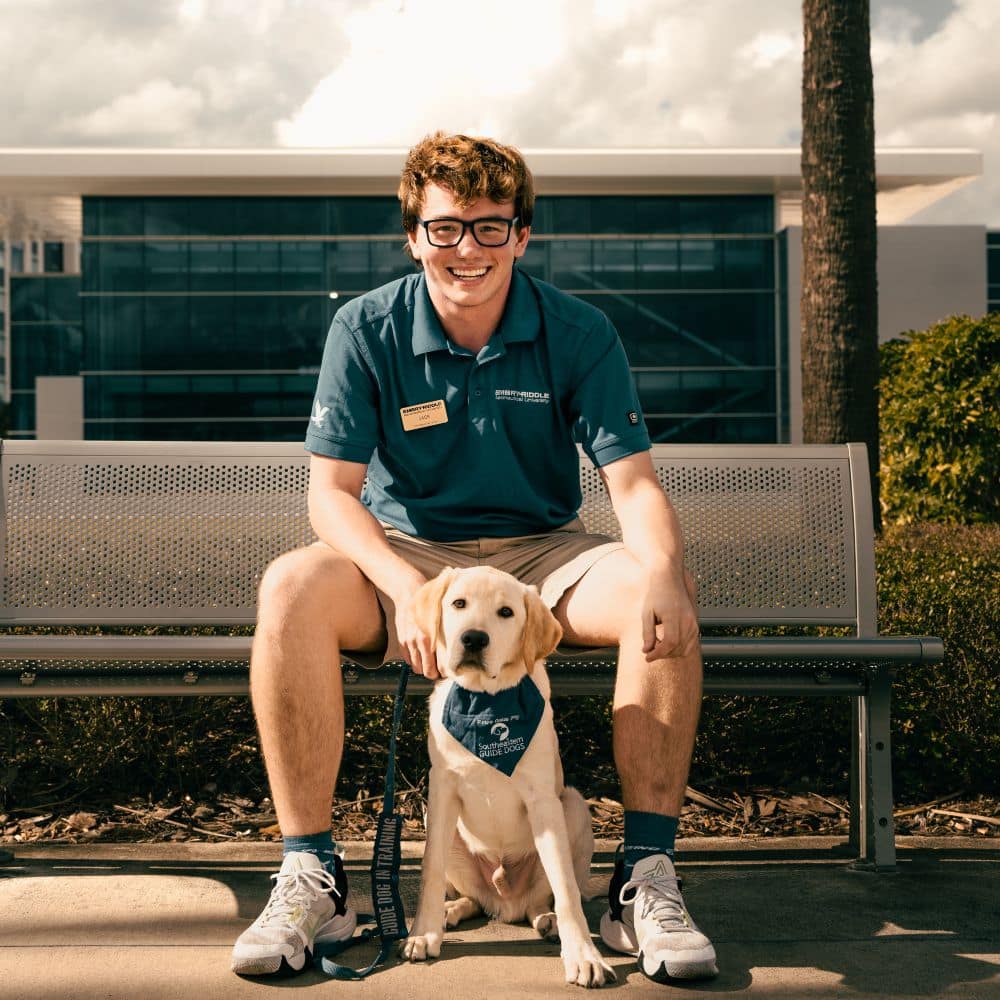 Jack Frankie ('25) with Harrison the Guide Dog who is training to be a future guide dog at the Daytona Beach Campus. (Photo: Embry-Riddle / Joseph Harrison)