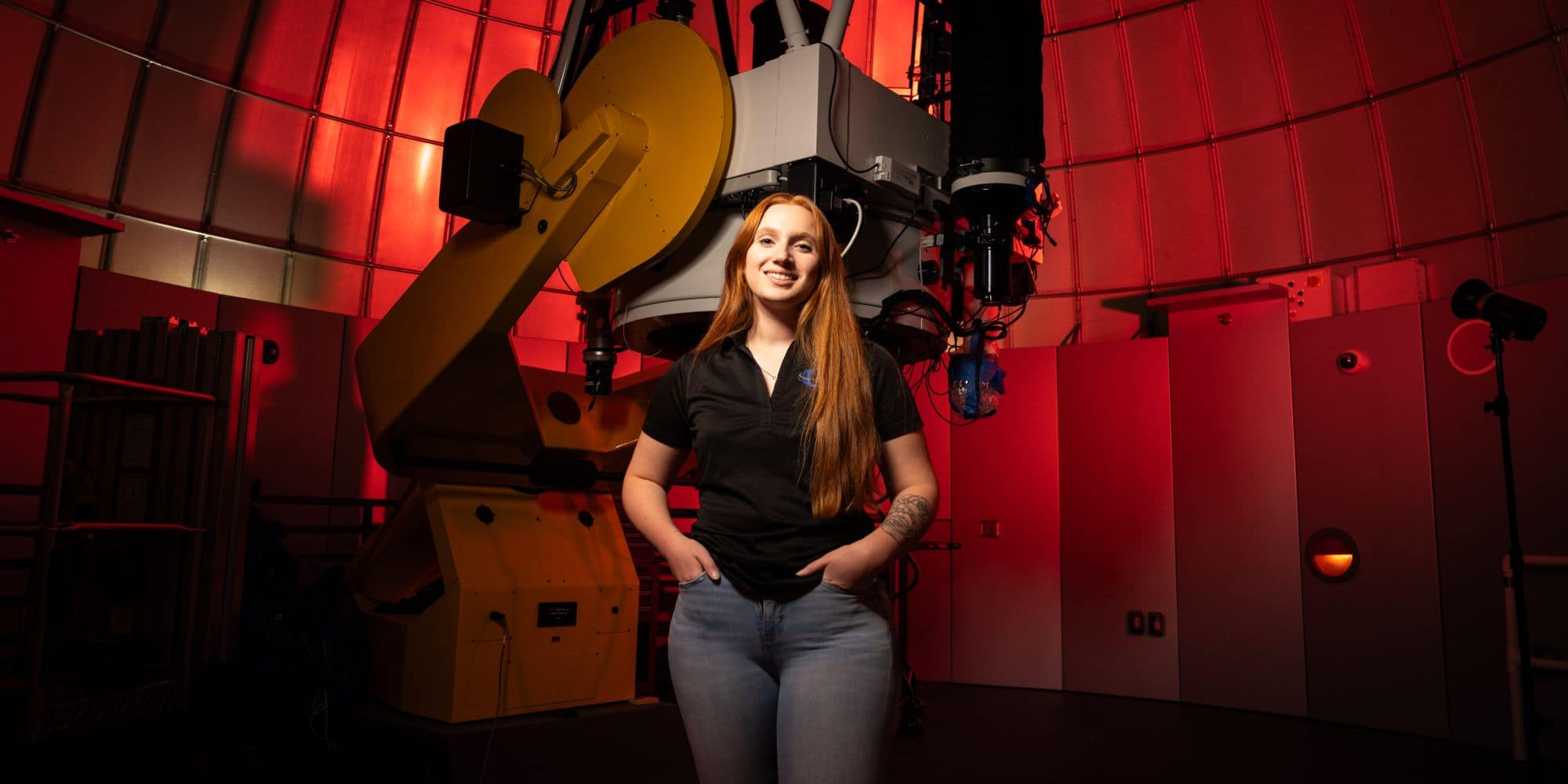 Astronomy and Astrophysics major Rhiannon Hicks standing in the Observatory, home to the largest university-based research telescope in the state of Florida.