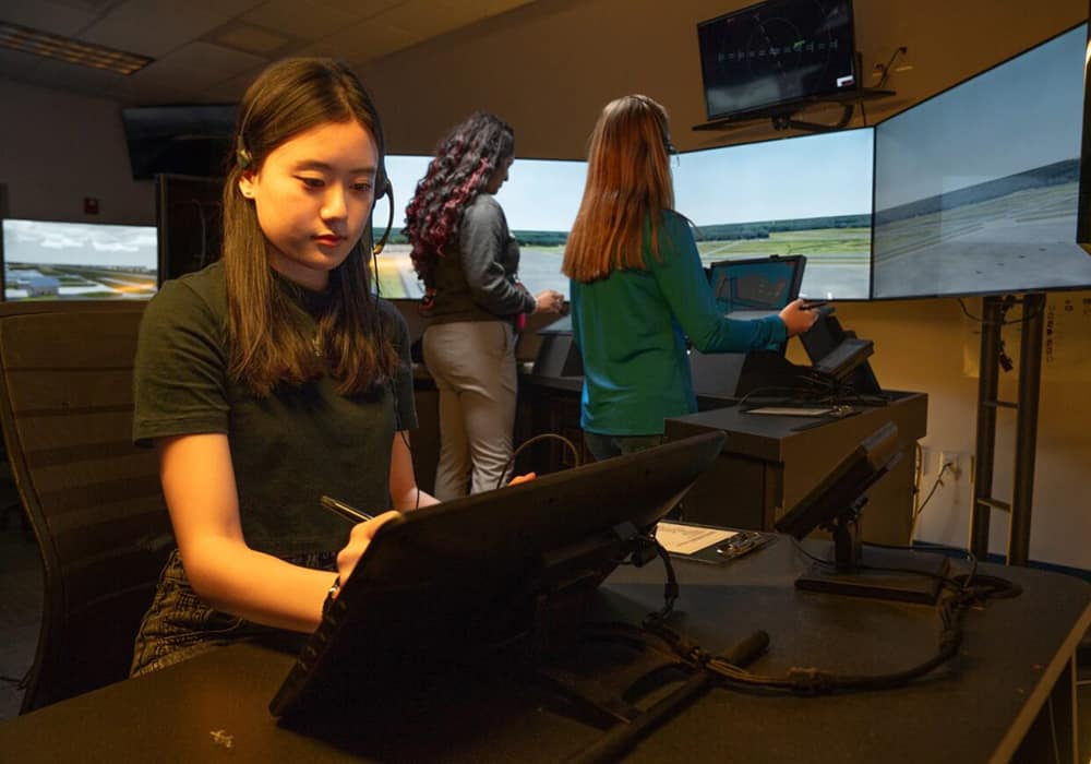 Three students work at a simulation terminal radar facility.