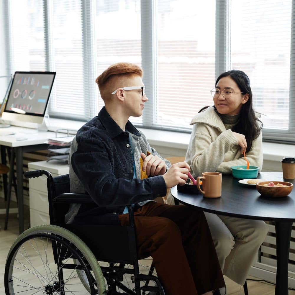 Two students sharing a meal at a table; one is using a wheelchair.