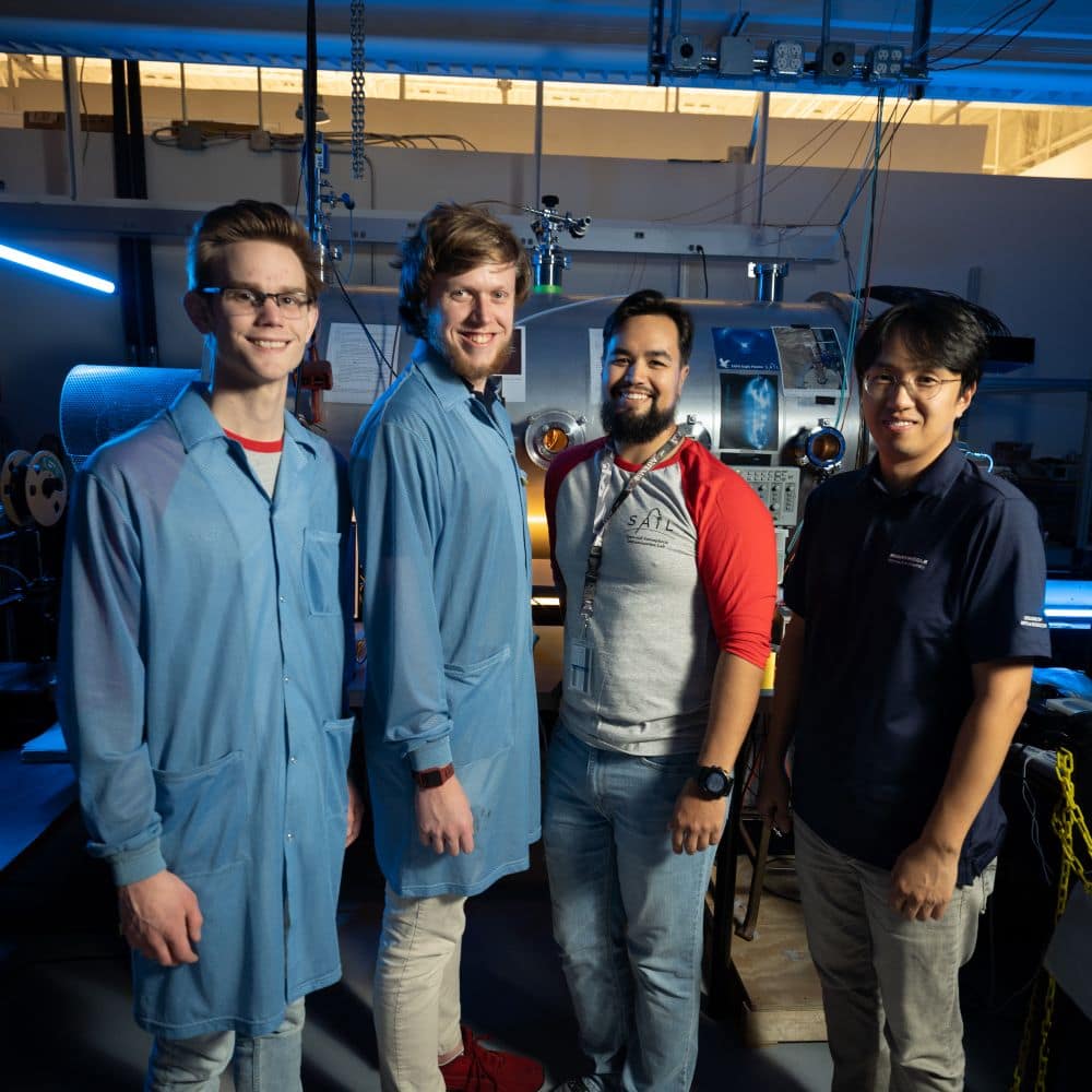(left to right) Undergraduate Jonas Rowan and graduate students Peter Ribbens and Marco Avila with Assistant Professor of Physics Dr. Byonghoon Seo in front of the plasma chamber. (Photo: Embry-Riddle / Bill Fredette-Huffman)
