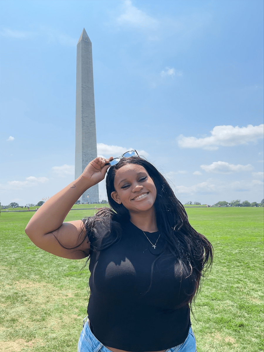 Shyan wears a black t-shirt and moves her sunglasses to the top of her head for a photo.