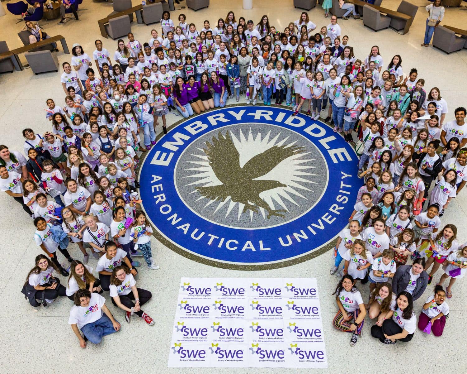 Students from Volusia County schools pose around the Embry-Riddle seal in the Mori Hosseini Student Union during a day-long workshop led by the Society of Women Engineers (SWE) Collegiate Section at the Daytona Beach campus on Feb. 11, 2023. (Photo: Embry-Riddle / Sergio Carli)