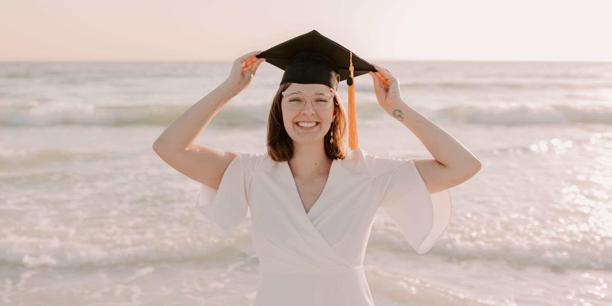 M.S. in Aviation grad Kayla Taylor celebrates completing her master’s program by modeling her graduation cap on the beach. (Photo: Alyssa Shrock)