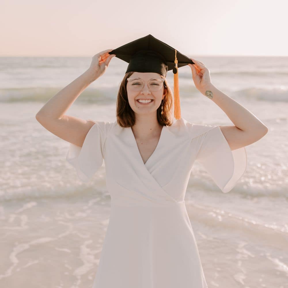 M.S. in Aviation grad Kayla Taylor celebrates completing her master’s program by modeling her graduation cap on the beach. (Photo: Alyssa Shrock)