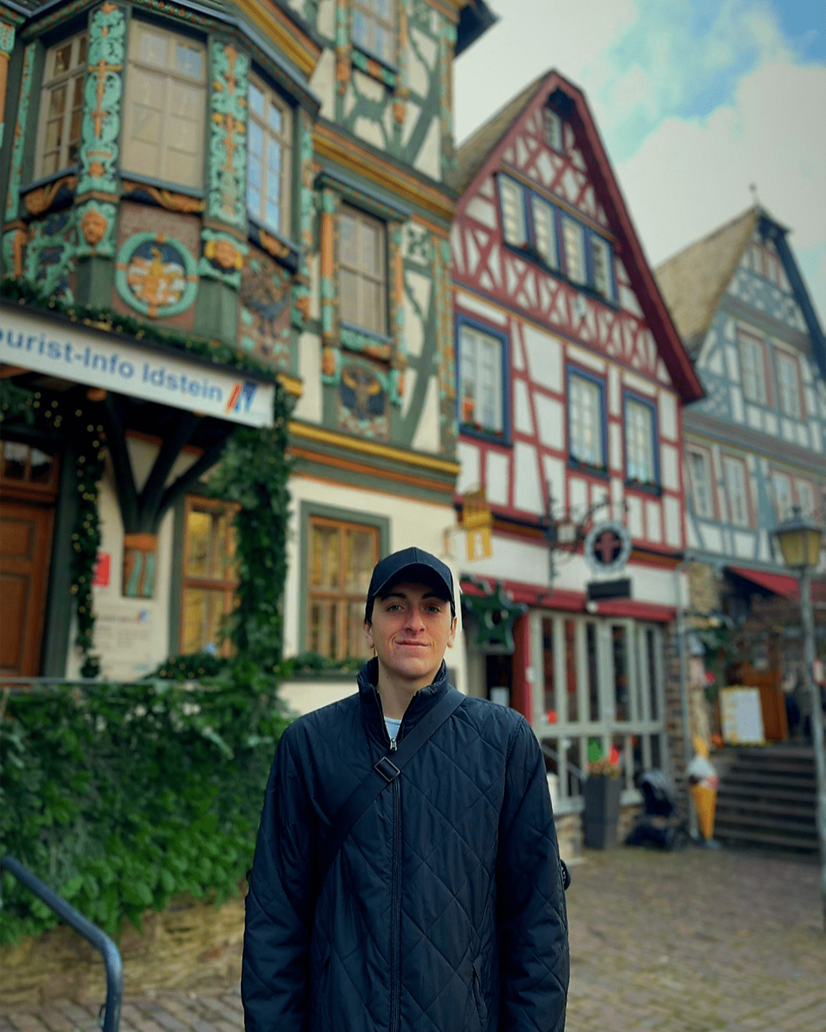 Zackrey stands in front of three colorful, half-timbered houses.