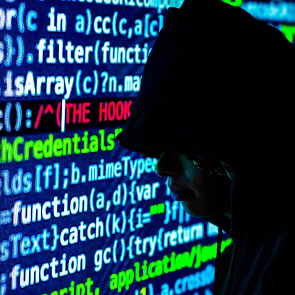 Man standing in front of a screen of computer code.