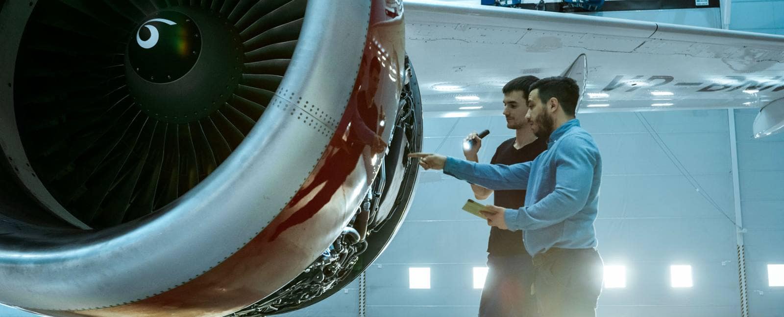 Two men look at a commercial airline engine