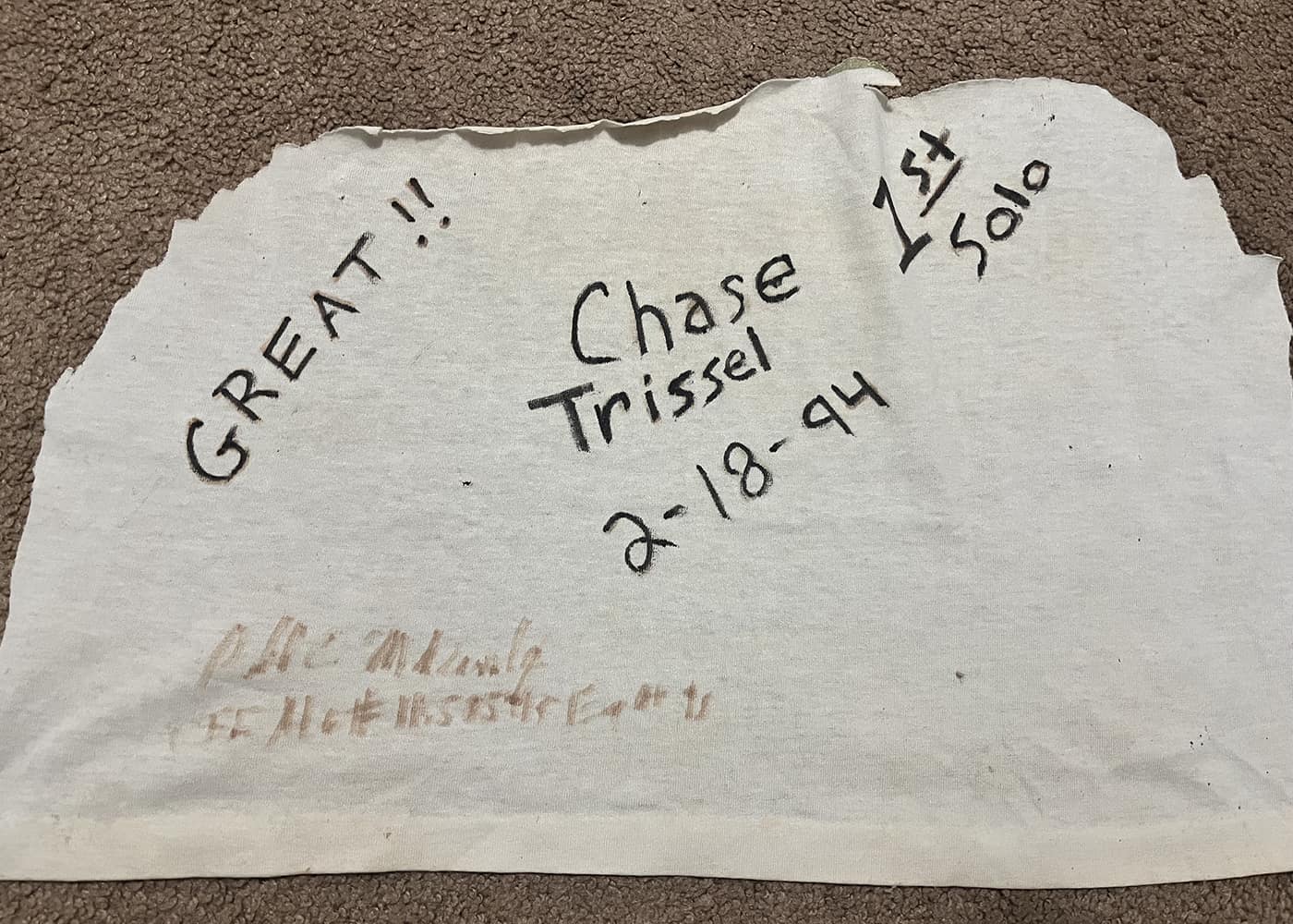 A white piece of cloth with notes written in black marker: Great! Chase Trissel 2-18-94, 1st solo.
