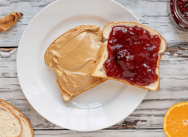 A plate with an open peanut butter and jelly sandwich.