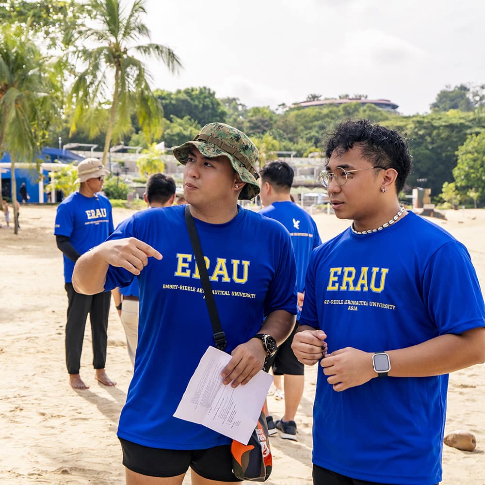 Two female students at an airshow take a picture in front of historical aircraft.