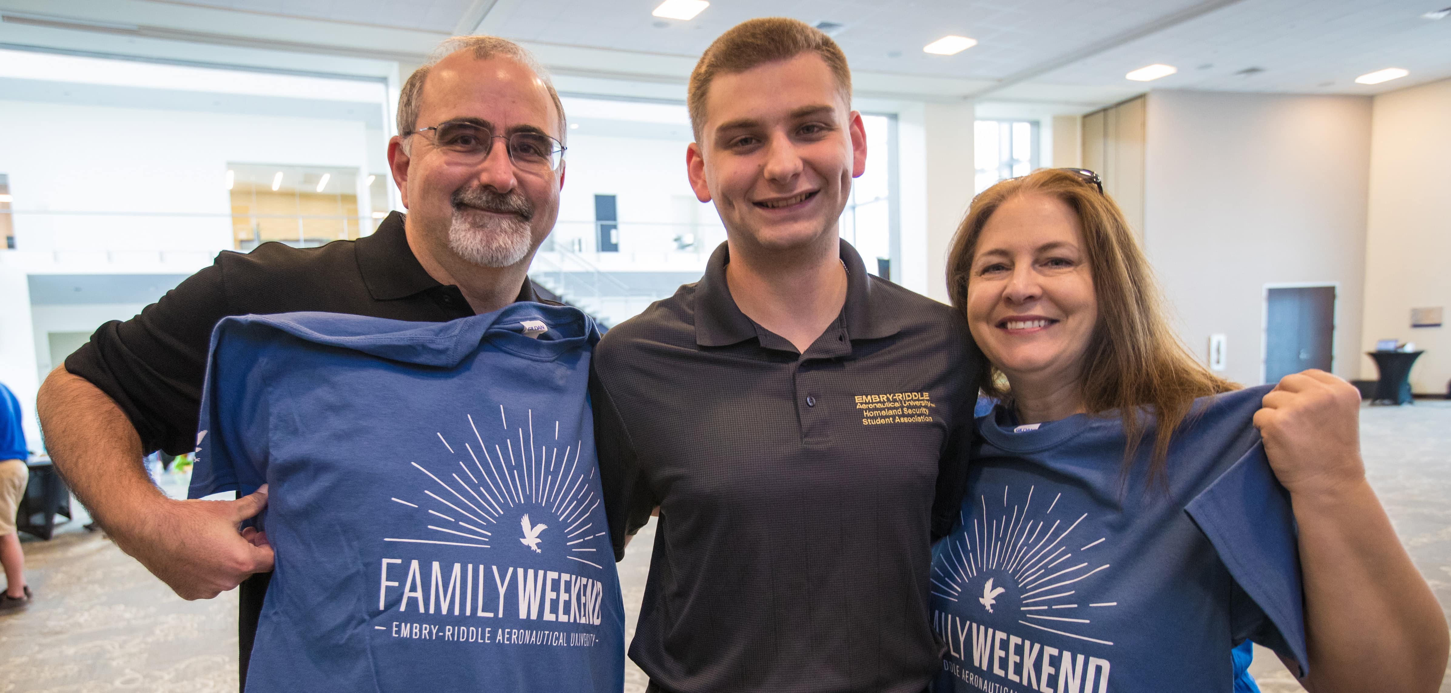 A family displaying their Family Weekend t-shirts.