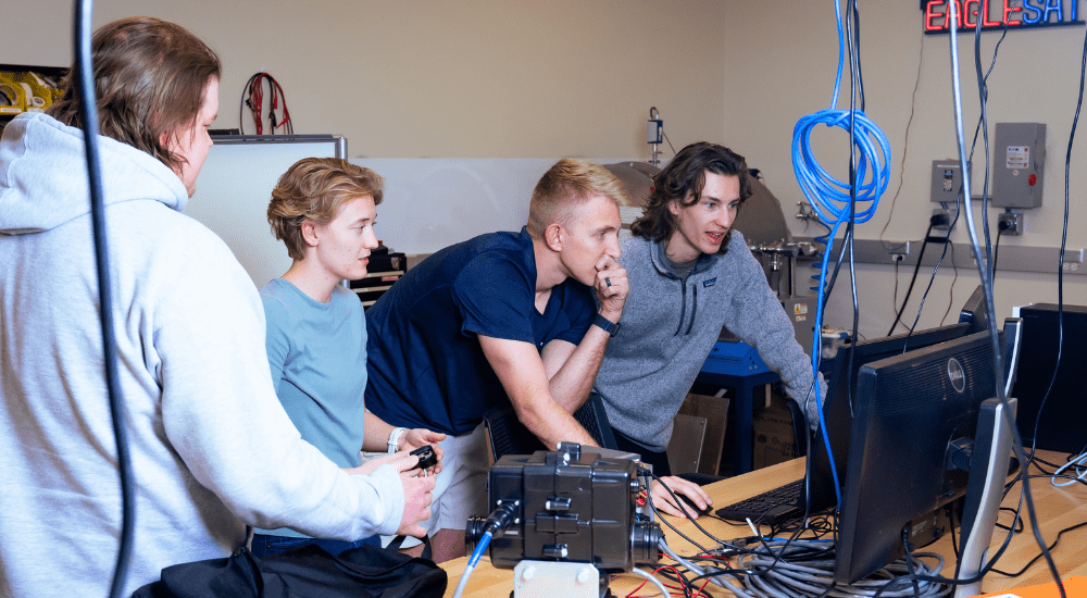 Matthew Gary and Parker Landon (capstone project contributors) along with Joshua Parmenter (OBC and ground station lead) and Hayden Roszell (OBC) achieve a breakthrough after testing numerous setups for connecting the ground station installed on the AXFAB roof to the EagleLab computers.
