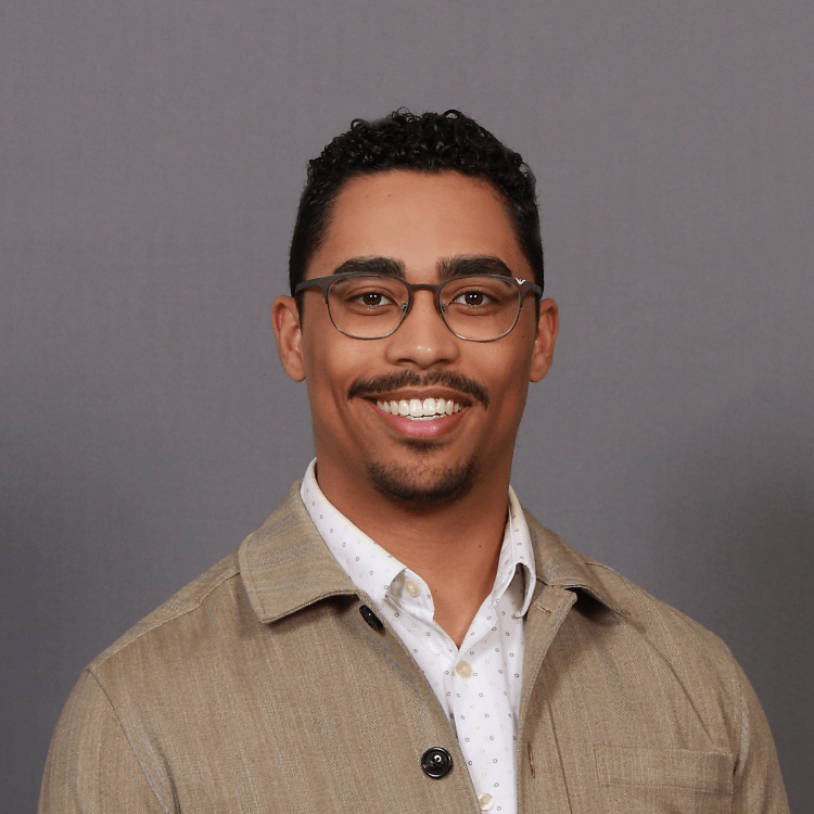 Gabriel smiles in front of a plain gray background.