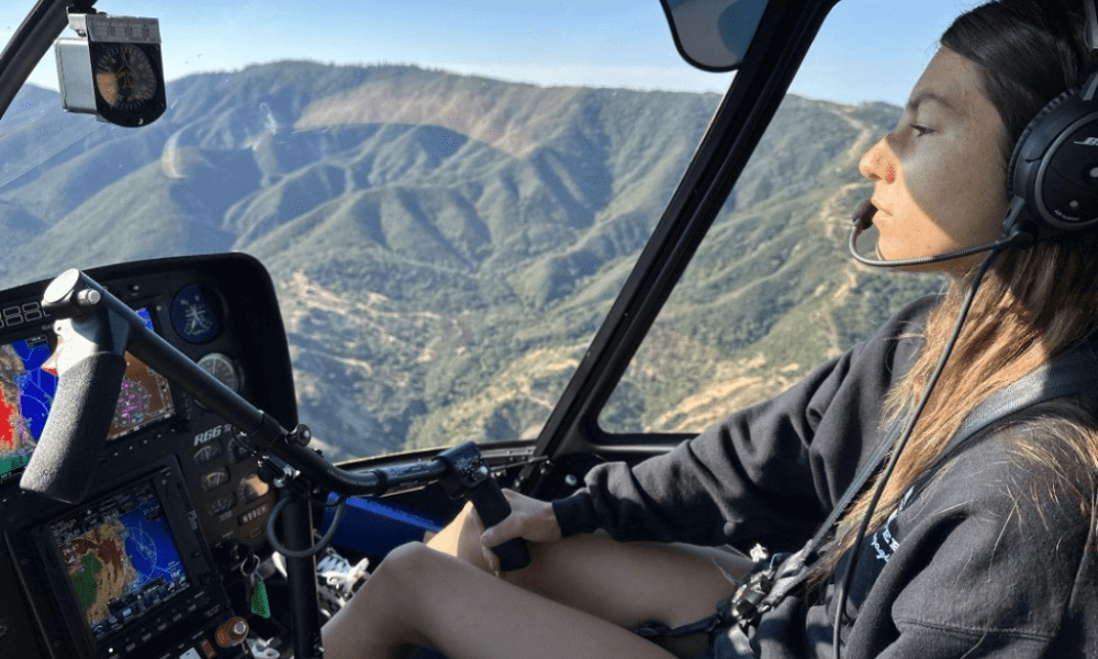 Nichole Stall piloting a helicopter over mountains.