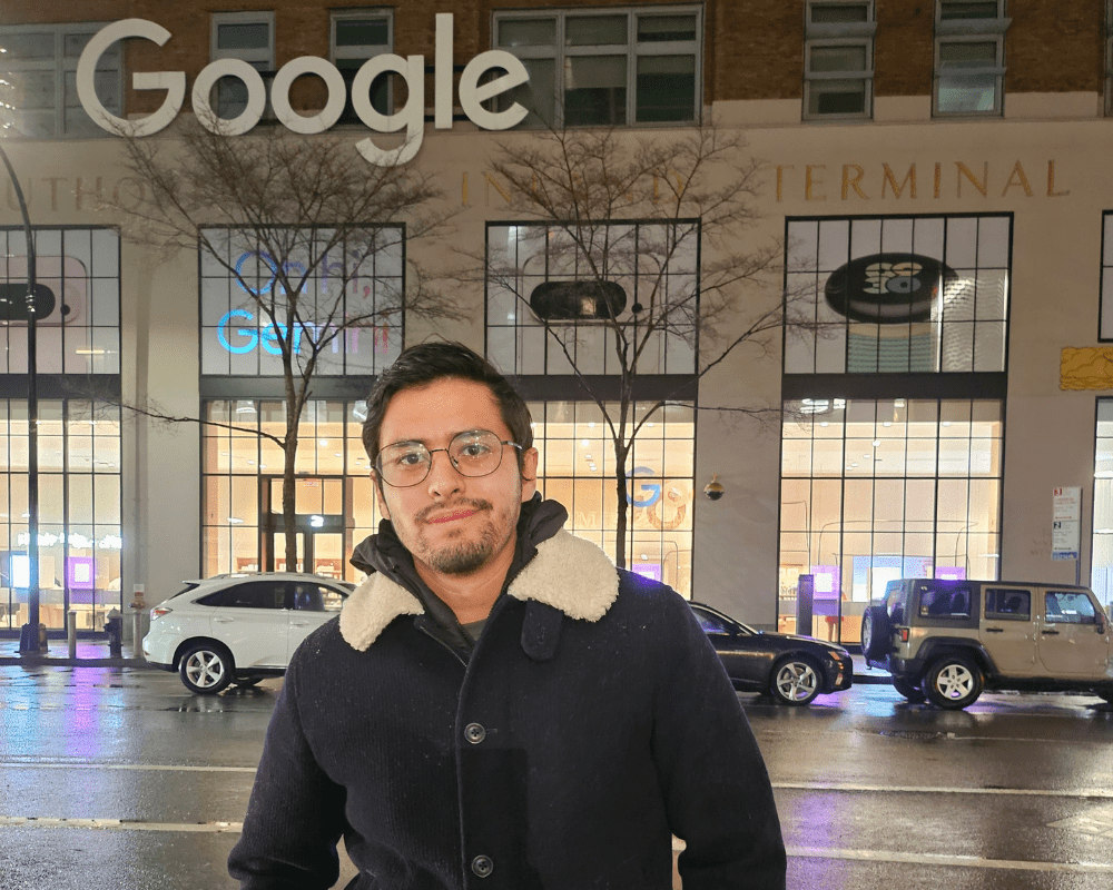A person standing in front of a building which says Google on the side.