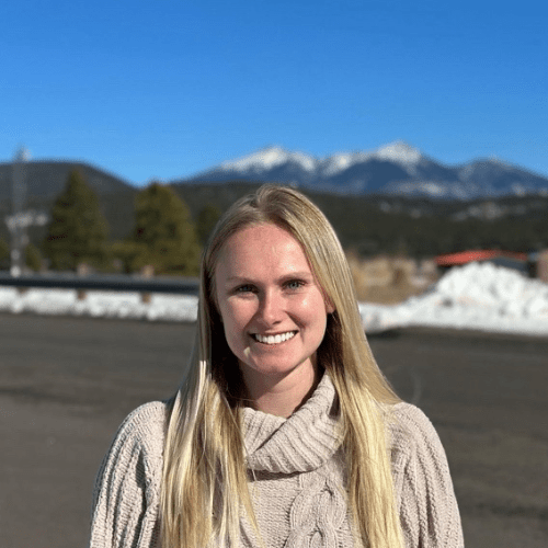 Paige Konieszny smiling, outdoors in a sweater.