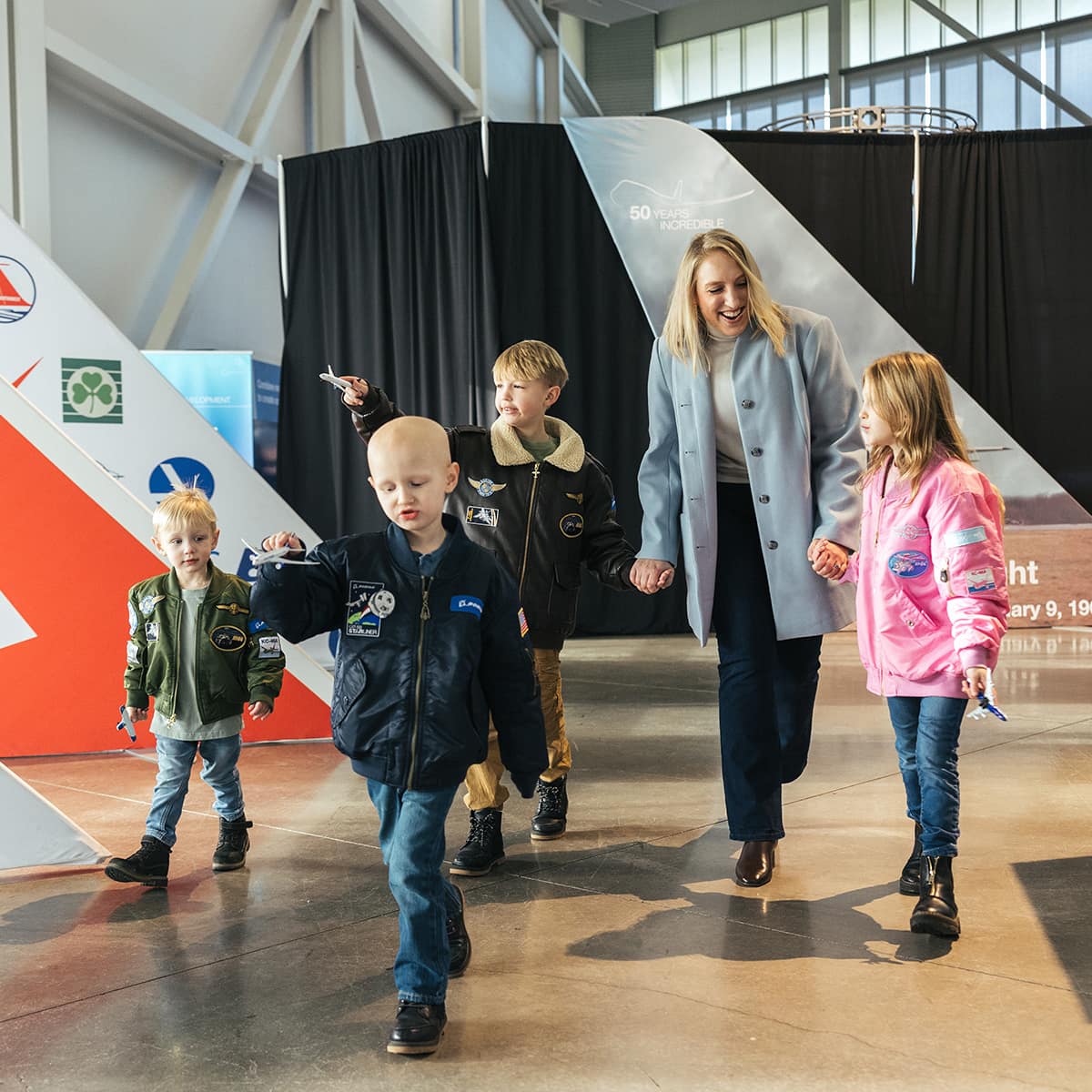 Blond woman and four blond children walking through a museum.