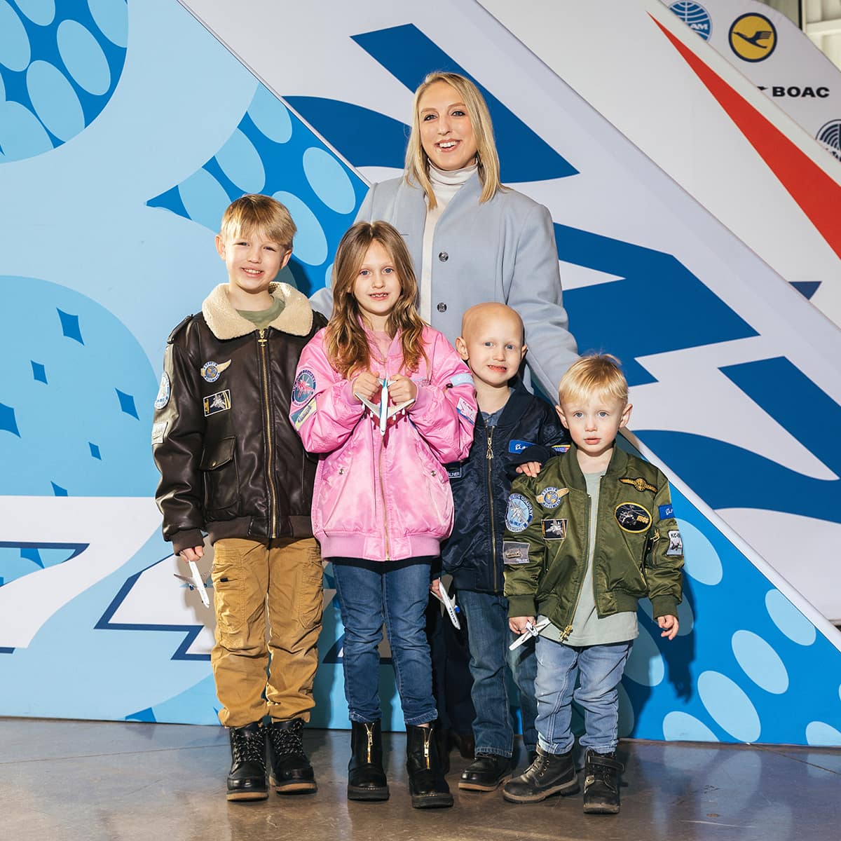 Rachelle stands in front of a 747 aircraft exhibit, her arms around her four children lined up by height.