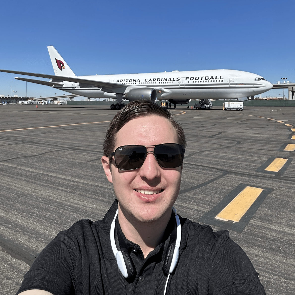 Timothy, his hair pulled back, stands in front of a jet on a clear day.