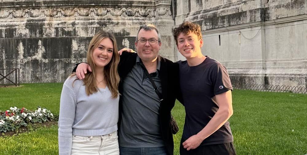 Christian poses with his family in front of an historic building.
