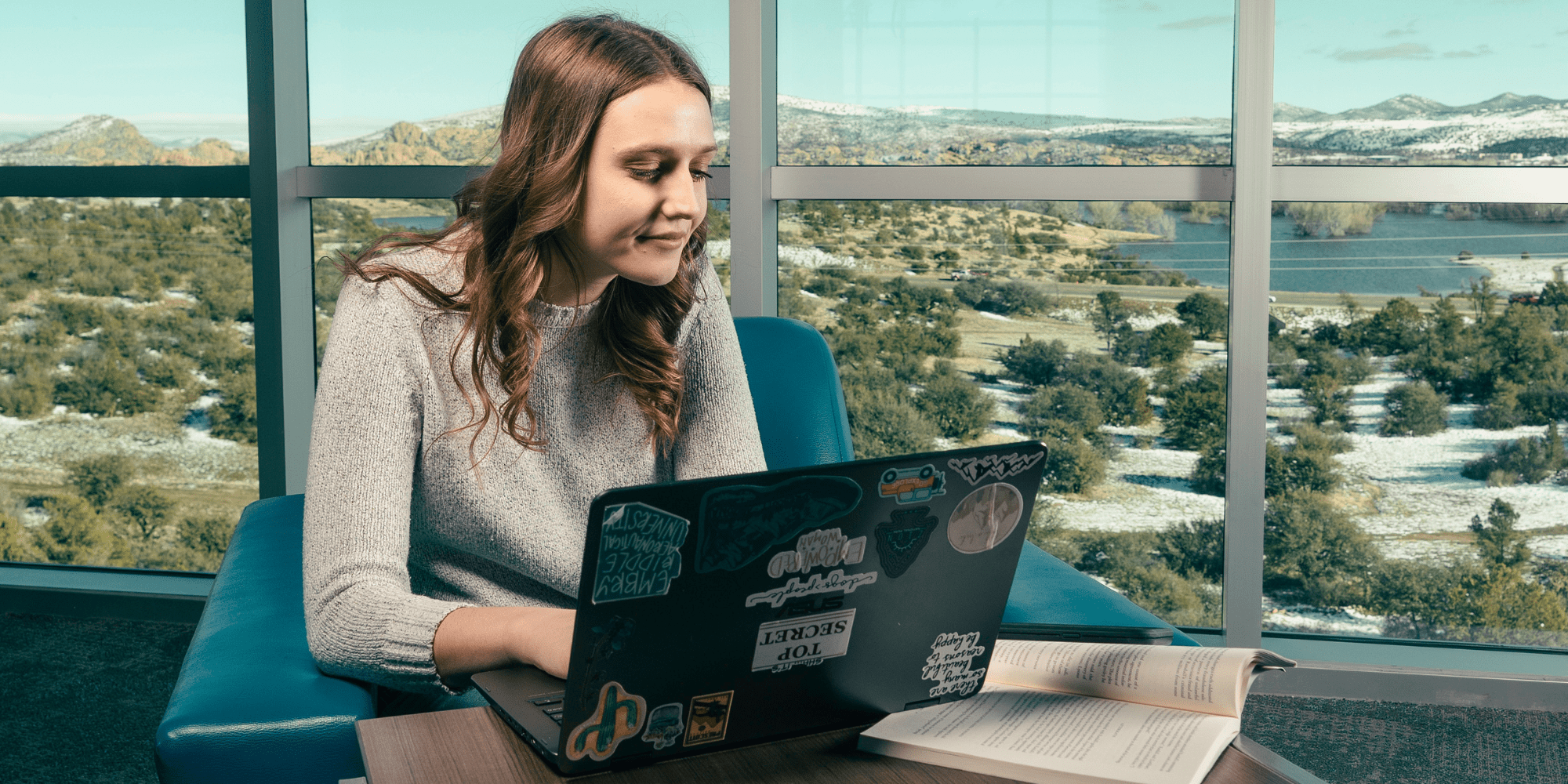 A student studies for tests in front of large windows.