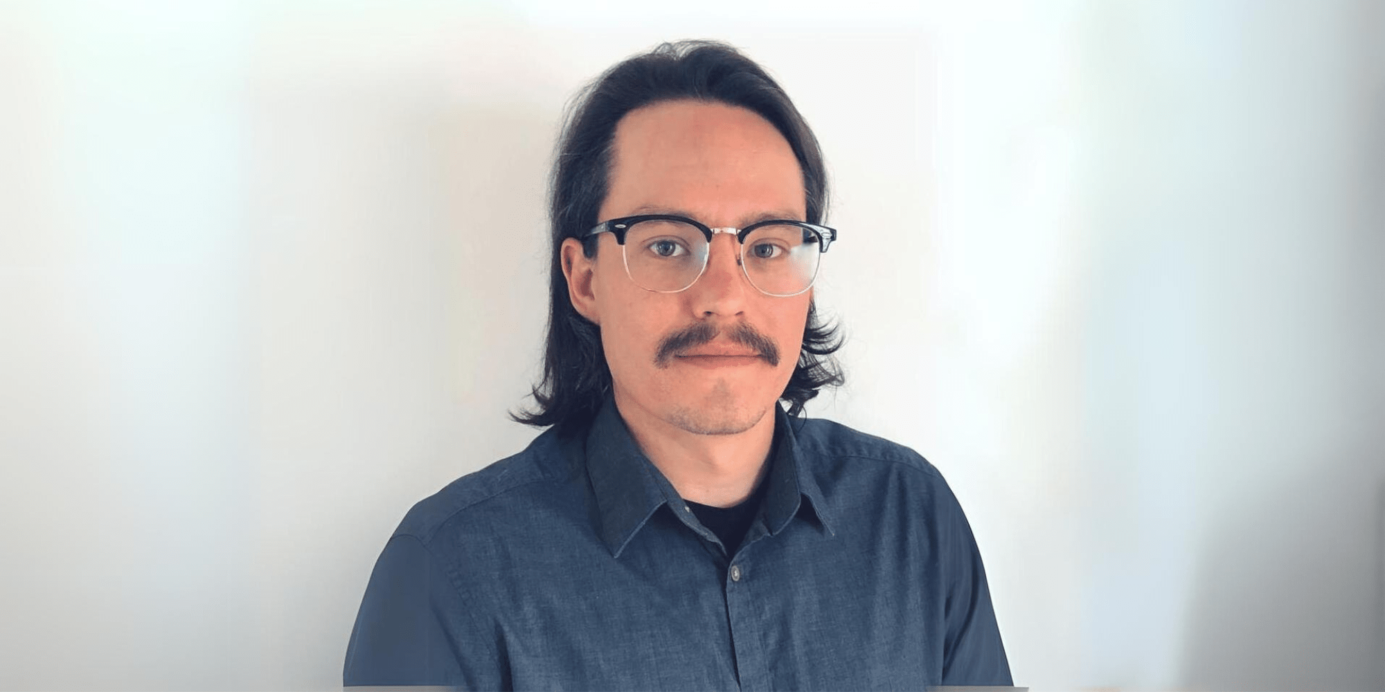 Headshot of Zach Grey in a dark blue button-up shirt.