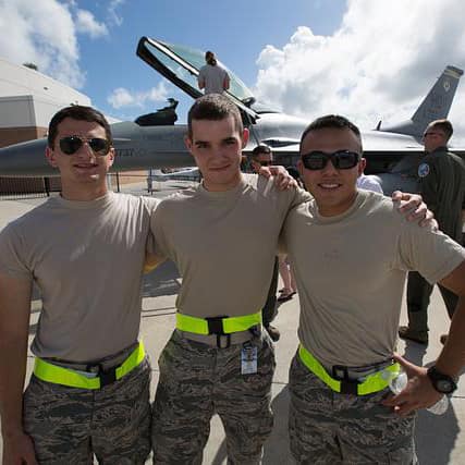 ROTC Air Force students embrace in front of a jet.