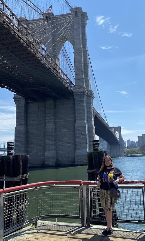 Woman posing for photo with the Brooklyn Bridge in the background