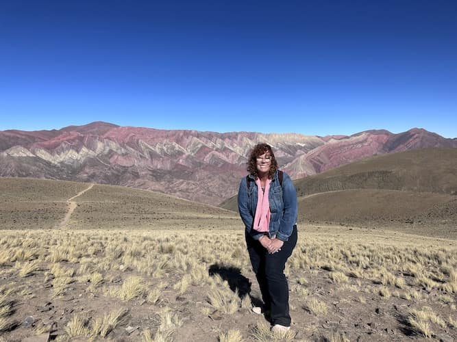 woman standing in open plain with mountains in the background
