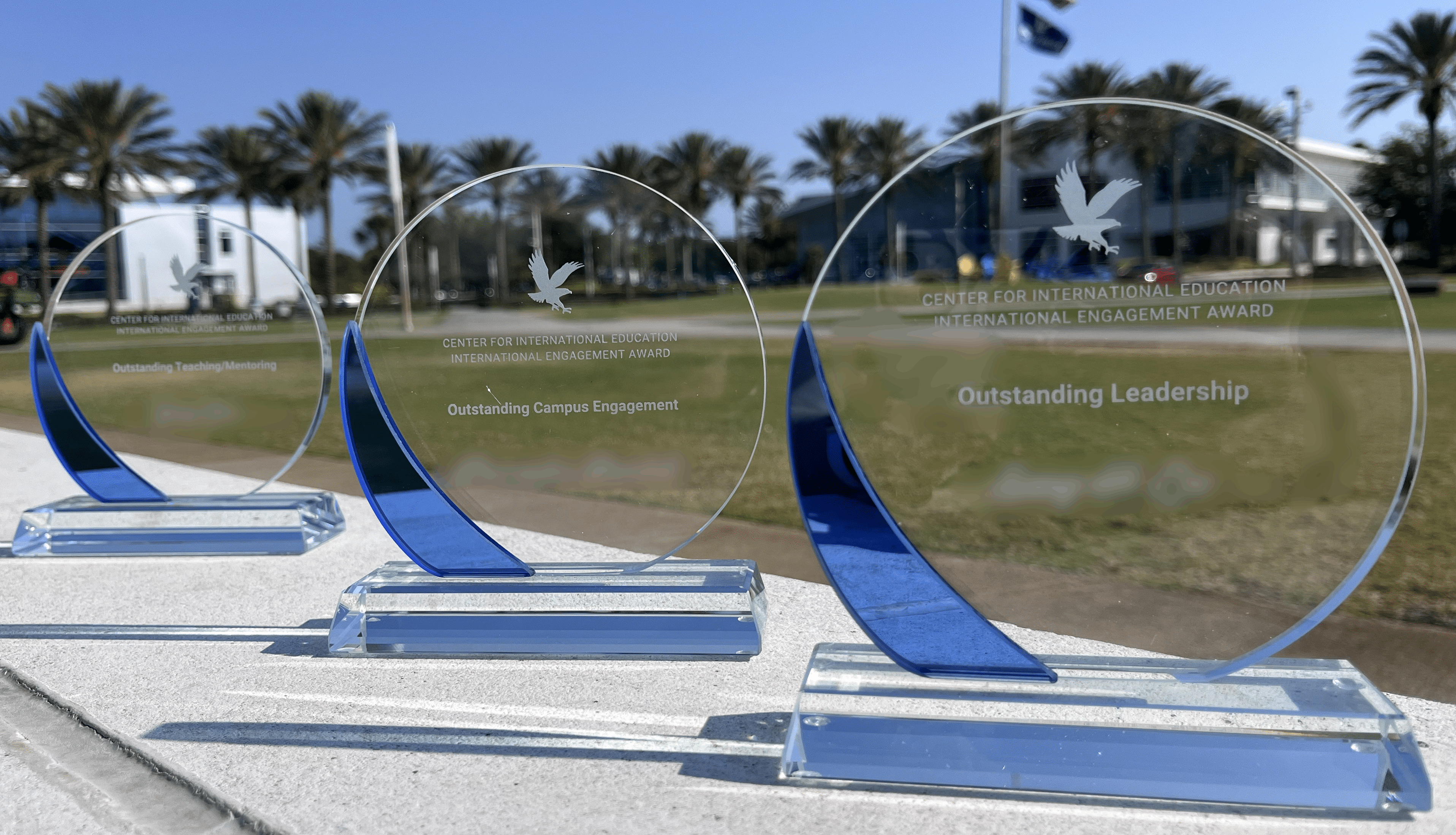 Three circular glass awards sitting on a wall outside.