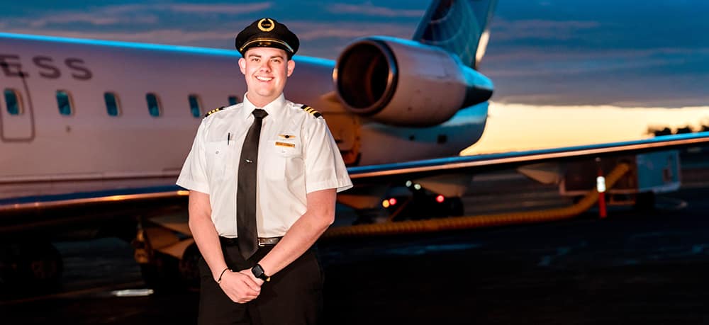 Embry-Riddle graduate in front of an airplane