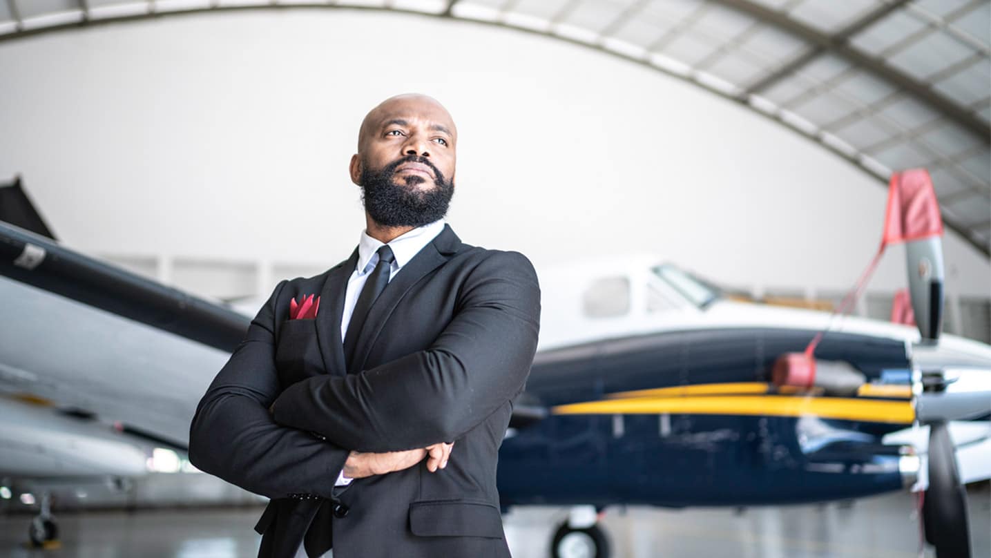 African American male in a suit with an airplane in the background