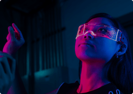 Person wearing a clear face shield looks upward under blue and magenta lighting.