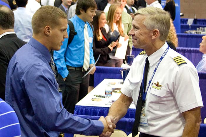 pilot shakes hands with a student at a job fair
