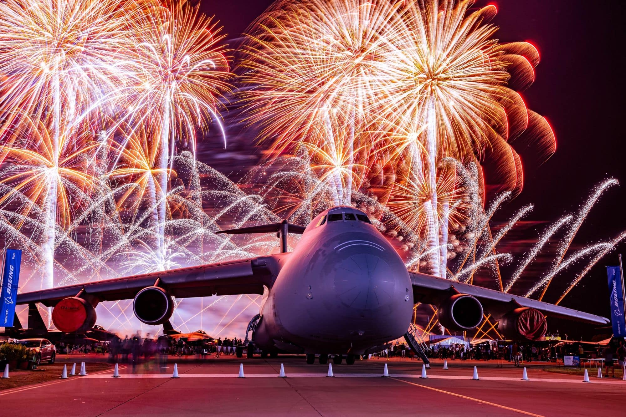 A Lockheed C-5A parked on an airport ramp with fireworks exploding behind it. (Photo: Wen Wu)